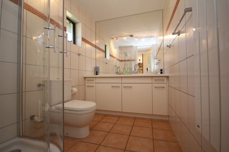 Moderne badkamer in vakantiehuis De Krim Texel, De Cocksdorp, met ruime douche en dubbele wastafel.
