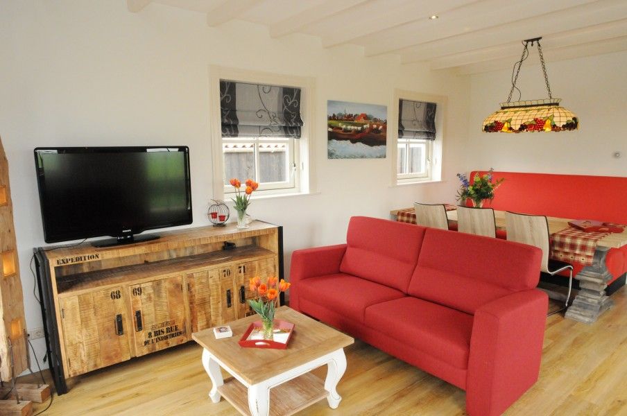 Gezellige woonkamer in vakantiehuis Sonja, Texel met comfortabele rode bank.