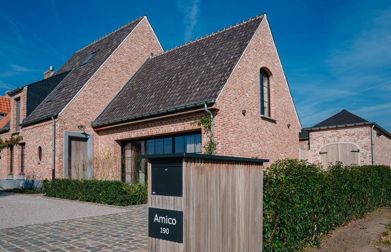 Charmant vakantiehuis in Gistel, Belgie met houten hek en groene haag, perfect voor een rustige vakantie in West-Vlaanderen.