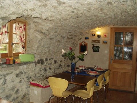 Charmante eetkamer met rustieke stenen muren in Ferme de Josephine, bed and breakfast in Le Bourg-d'Oisans, Rhone-Alphes, Frankrijk.
