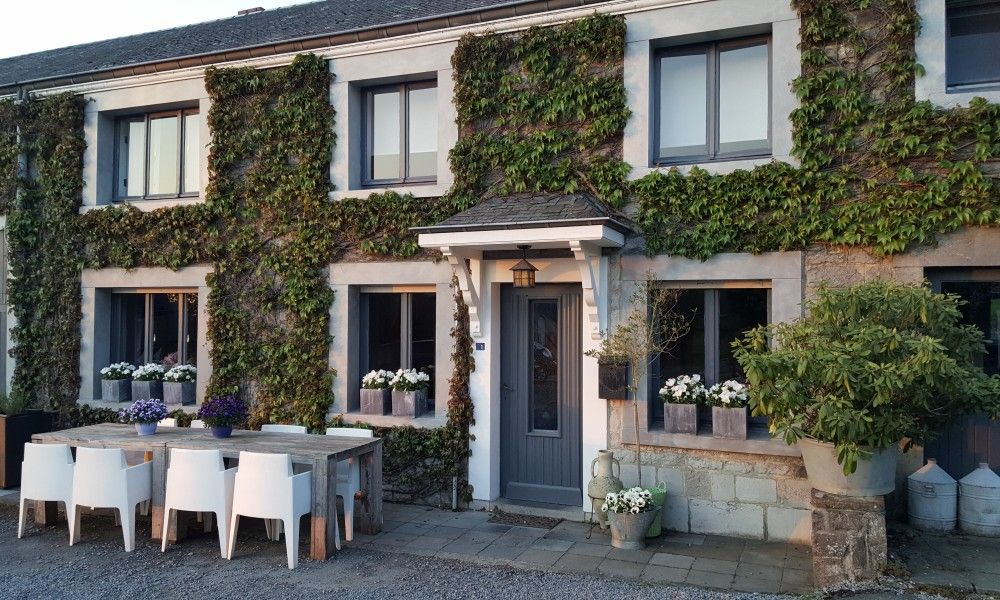 Charming vacation home Au Foyer in Durbuy, Ardennes with green facade and inviting terrace.