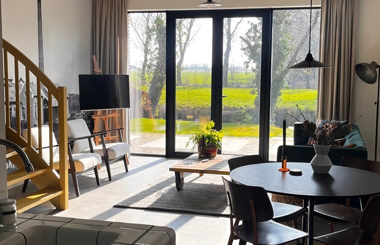 Lichte woonkamer in Vakantiehuisje in Lioessens met uitzicht op het Friese platteland, Friesland.