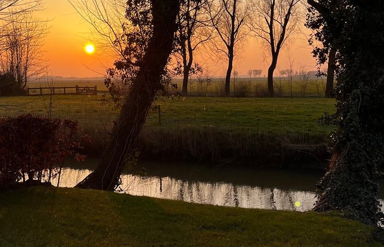 Rustgevende zonsondergang aan het water bij Vakantiehuisje in Lioessens, Friesland, op het platteland.