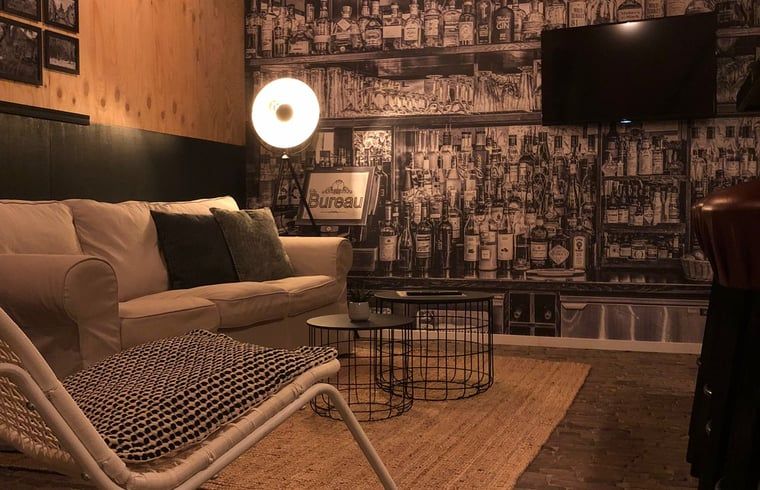 Sfeervolle woonkamer in Vakantiehuis in 't Harde, Veluwe, met unieke wanddecoratie.