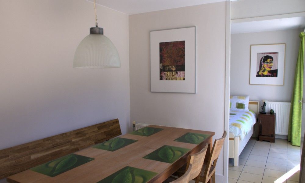 Eetkamer met houten tafel in Kussengevecht Duinvilla, Den Haag, vakantiehuis aan de Noordzeekust, grenzend aan lichte slaapkamer.