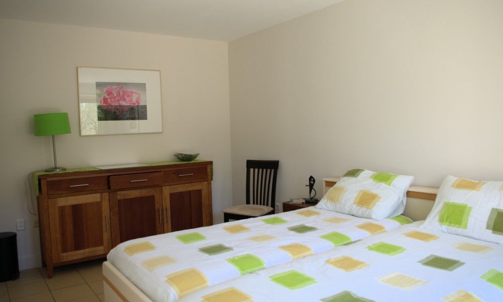 Ruime slaapkamer in Kussengevecht Duinvilla, Den Haag, vakantiehuis aan de Noordzeekust met tweepersoonsbed en houten meubelen.