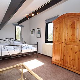 Sfeervolle slaapkamer in De Krim Texel, De Cocksdorp, met houten kast en comfortabel tweepersoonsbed.