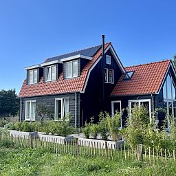 Buitenzijde van vakantiehuis Paal 234 in De Koog, Texel, omgeven door groene natuur.