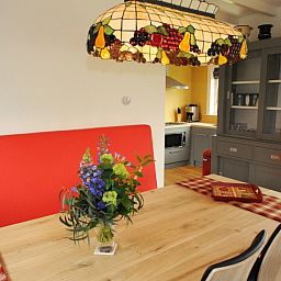 Eethoek met kleurrijke lamp in vakantiehuis Sonja, Texel, ideaal voor familiediners.