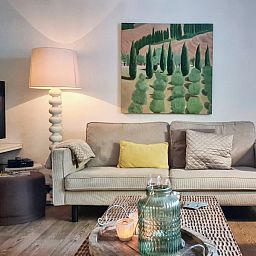 Atmospheric living room in vacation home Au Foyer, Durbuy, with artwork and soft lighting.