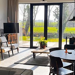 Lichte woonkamer in Vakantiehuisje in Lioessens met uitzicht op het Friese platteland, Friesland.
