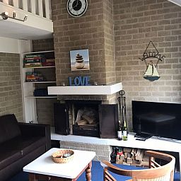 Cozy living room with fireplace in Huisje Blauw, vacation accommodation in Bruinisse, Zeeland.