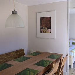 Eetkamer met houten tafel in Kussengevecht Duinvilla, Den Haag, vakantiehuis aan de Noordzeekust, grenzend aan lichte slaapkamer.