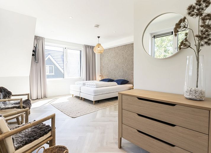 Stijlvolle entree van Villa 8 Pers. op Vakantiepark So What, Texel met houten trap en kunstzinnige muurschildering.