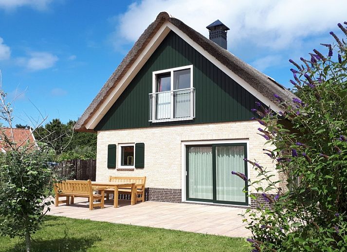 Entree van Duinrand Vakantievilla's Type 2 in De Koog, Texel, omgeven door kleurrijke bloemen en groene natuur.