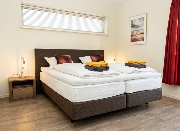 Zonnig terras bij Duinrand Vakantievilla's Type 2, een vakantiehuis in De Koog, Texel, met houten tuinmeubilair.