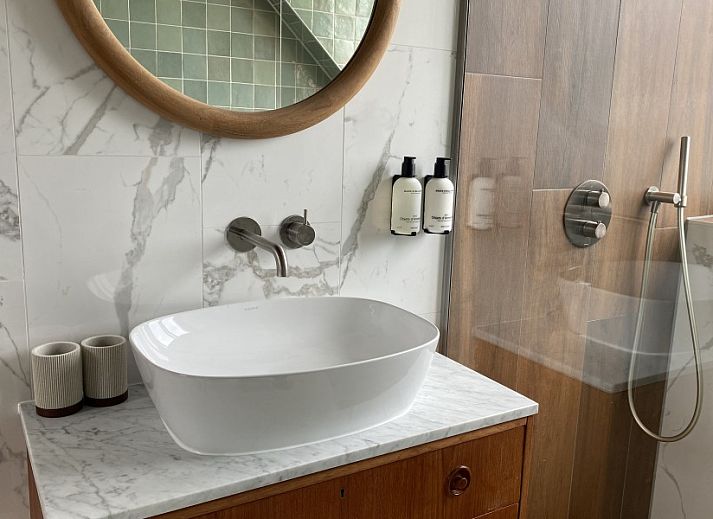 Stijlvolle woonkamer van Paal 234, een vakantiehuis in De Koog, Texel, met leren bank en vintage decor.