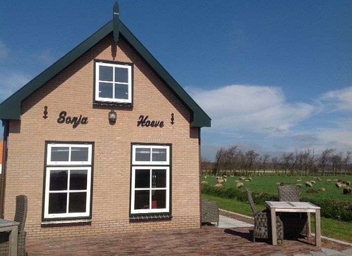 Gezellige woonkamer in vakantiehuis Sonja, Texel met comfortabele rode bank.