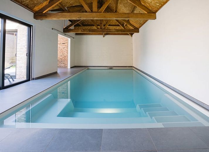 Charmant vakantiehuis in Gistel, Belgie met houten hek en groene haag, perfect voor een rustige vakantie in West-Vlaanderen.