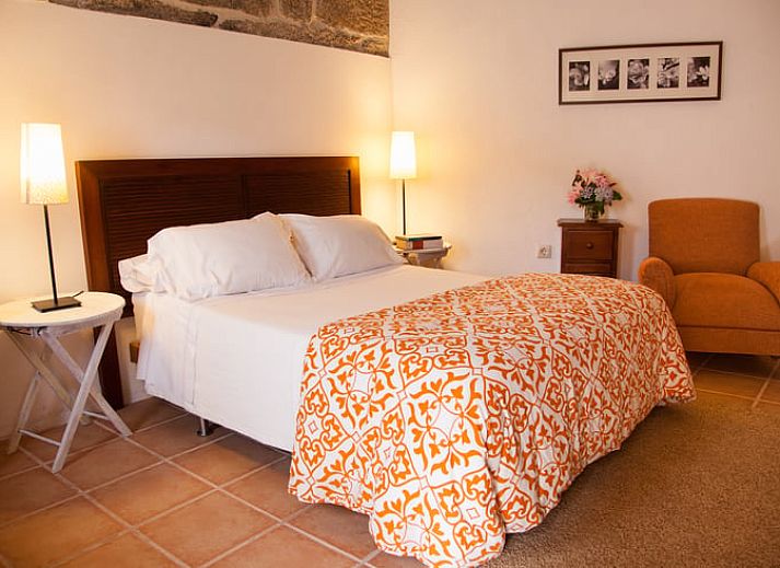 Rustieke charme in Vakantiehuis in A Lama, Het groene Spanje, met een uitnodigende slaapkamer en authentieke stenen details.