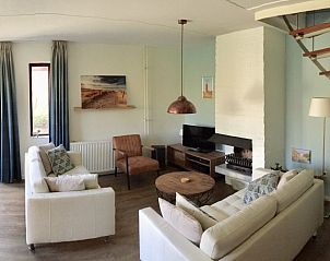 Moderne woonkamer in Het Zonneveld vakantiewoning op Texel met open haard.