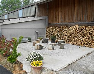 Buiten zitgedeelte bij Hof ter Harte vakantiehuis, Ieper, West-Vlaanderen met houten banken en bloemen.