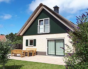 Zonnig terras bij Duinrand Vakantievilla's Type 2, een vakantiehuis in De Koog, Texel, met houten tuinmeubilair.