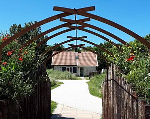 Ingang van Duinrand Vakantievilla's Type 2 in De Koog, Texel, met houten poort en bloeiende tuin.