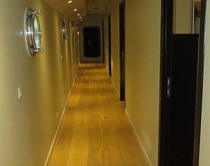 Lange gang in Bed in Boat, Ieper, West-Vlaanderen, met houten vloeren en patrijspoorten.