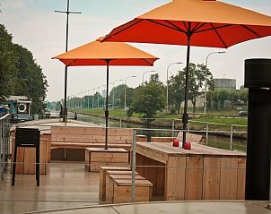 Ruim terras op Bed in Boat, Ieper, West-Vlaanderen, met zitgelegenheid en oranje parasols.
