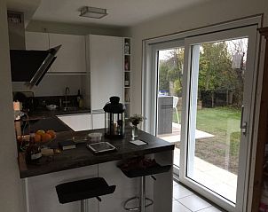 Keuken met uitzicht op tuin in Huize 100-1, vakantiehuis in De Koog, Texel, perfecte plek voor culinaire creaties.