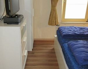 Comfortabele slaapkamer in huisje 149, De Koog, Texel, met een groot raam dat natuurlijk licht binnenlaat op de Waddeneilanden.