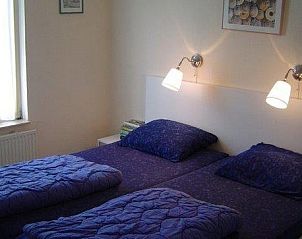 Sfeervolle slaapkamer met tweepersoonsbed in huisje 149, De Koog, Texel, biedt een rustige plek om te ontspannen op de Waddeneilanden.