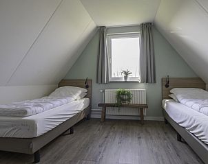 Sfeervolle slaapkamer met twee bedden in Nieuwlanderweg 75 bungalow, De Koog, Texel, met uitzicht op de natuur.