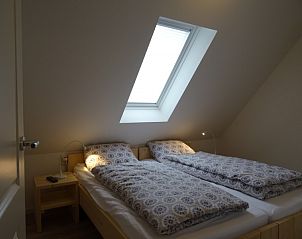 Sfeervolle slaapkamer met dakraam in De Vigilant vakantiehuis, Den Hoorn, Texel, ideaal voor een rustgevende nacht op de Waddeneilanden.