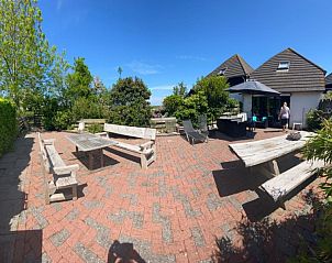 Ruim terras van de Jutter in Oost, Texel, met tuinmeubelen en groene omgeving.