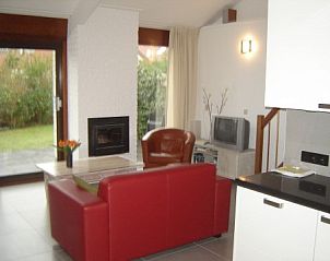 Lichte woonkamer met open haard in Bungalowpark Gortersmient, Texel, biedt gezelligheid in het Dennenbos.