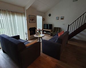 Knusse woonkamer in Alkema bungalowverhuur Gortersmient, Texel, met grote ramen en tv.