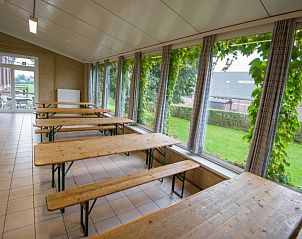 Lichte eetruimte in De Bosgeus vakantiehuis in Nieuwkerke, West-Vlaanderen met uitzicht op de tuin.