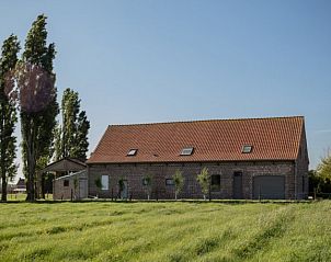 Prachtig uitzicht op onZENhof, een vakantiehuis in Heuvelland, omgeven door groene velden en hoge bomen.