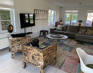 Gezellige woonkamer in St Kwintens vakantiehuis, Knokke-Heist, met moderne meubels en kleurrijk tapijt.