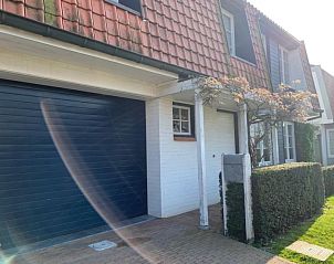 Ingang van St Kwintens vakantiehuis in Knokke-Heist, Belgi met garage en bloeiende heg.