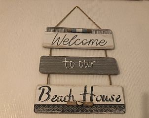 Welkomstbord in Mamre Beach Condo, Oostende, dat gasten verwelkomt in het strandhuis.