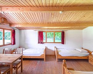 Houten slaapkamer in Vakantiehuisje in Vrees, Nedersaksen met uitzicht op de tuin en comfortabele bedden.