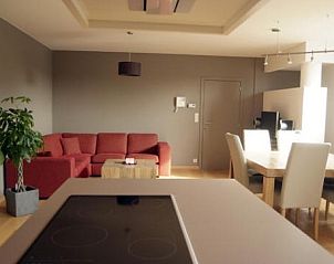 Stijlvolle woonkamer in Amalia appartement, Oostduinkerke, met comfortabele bank en eetruimte.