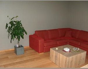 Knusse zithoek in Amalia appartement, Oostduinkerke, met rode bank en houten salontafel.