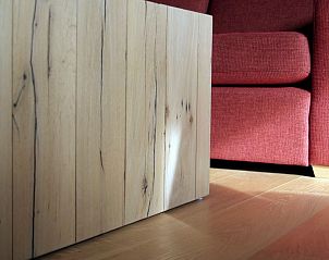 Detail van houten salontafel en rode bank in Amalia appartement, Oostduinkerke.