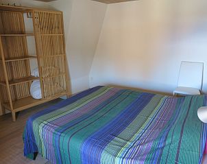 Ruime slaapkamer met kleurrijk beddengoed in De Mutsaard, vakantiehuis in Oost-Vlaanderen.