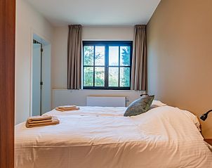 Slaapkamer in 't Klooster vakantiehuis in Loonbeek, Vlaams-Brabant met een comfortabel tweepersoonsbed en uitzicht op de groene omgeving.