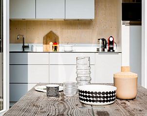 Cozy dining area in Florizand vacation home, Midsland Noord, Terschelling with crockery and open kitchen.